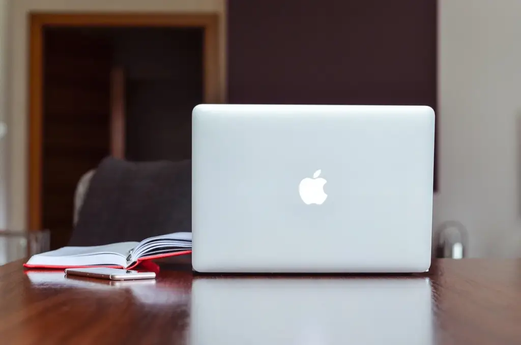 person working on laptop on desk with notebook
