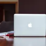 person working on laptop on desk with notebook